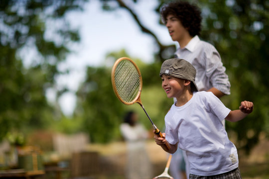 Young boy and his older brother playing badminton