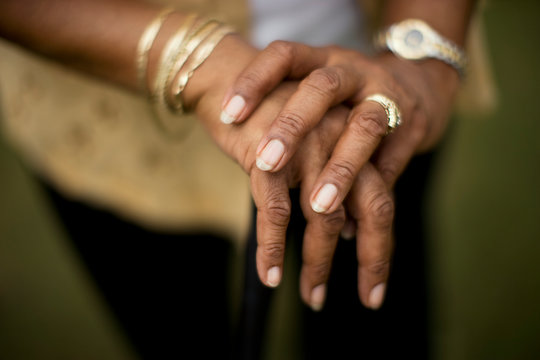Mature woman's hands adorned with gold jewelry.