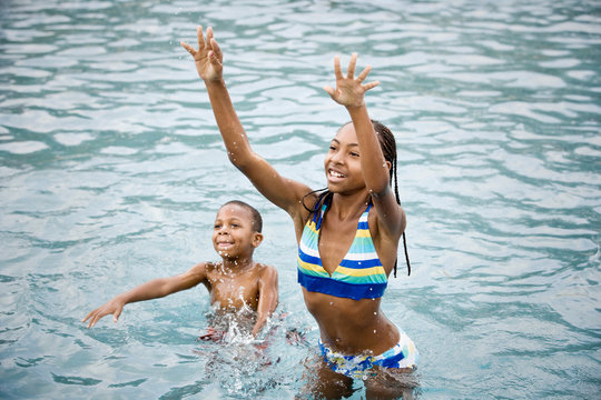 Teenage girl and her younger brother playing together in the sea.