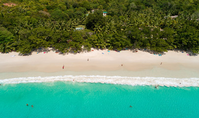 Aerial view of sandy beach with tourists swimming in beautiful clear sea water