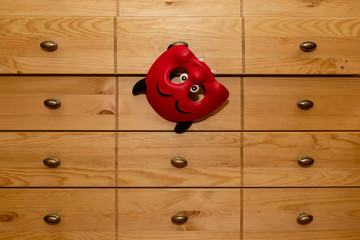 The carnival mask hangs on the chest of drawers.