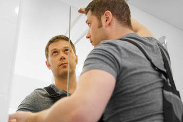 Obraz premium Handyman installing glass cabinet in bathroom.
