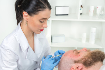 The doctor cosmetologist makes the Rejuvenating facial injections procedure for tightening and smoothing wrinkles on the face skin of a men in a beauty salon.Cosmetology skin care.