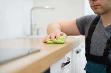 Cleaning service concept. Man cleaning kitchen furniture.