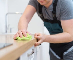 Cleaning service concept. Man cleaning kitchen furniture.
