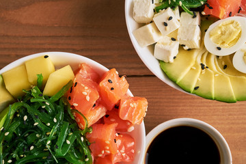 Raw Organic Poke Bowl with rice, avocado, salmon, mango, cucumbers, chuka salad, quail eggs, sweet...