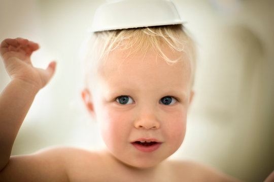 Portrait of a young toddler wearing a bowl on his head.