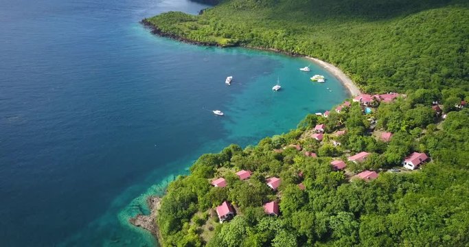 Drone flying over a Tropical paradise beach surrounded by water and rainforest in the Caribbean sea with boats
