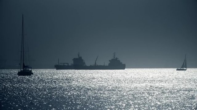 Silhouettes of sailboats and cargo ship near Gibraltar