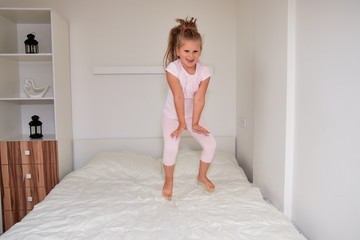 Little girl jumping on bed at home