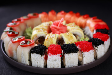 food art, traditional japanese seafood, restaurant menu photo. great colorful set of fresh maki sushi rolls served in black porcelain plate