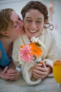 Women lying on floor in house with orange juice and flowers