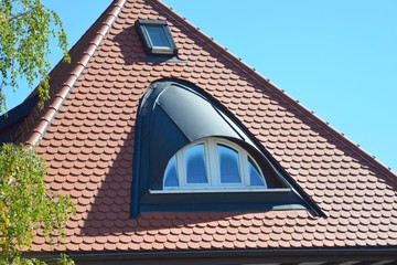 Stehfalz-Metall- Rundbogengaube und Dachfenster in einem mit Biberschwanzziegeln gedeckten...
