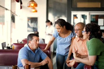 Smiling friends meeting for coffee at a local diner.