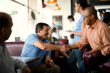 Smiling friends meeting for coffee at a local diner.
