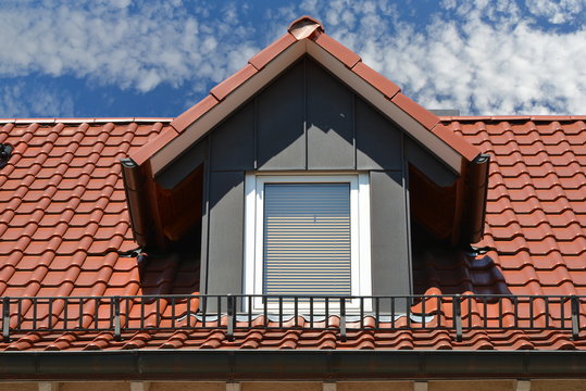 Dachgaube in kupferfarben beschichteter Stehfalz-Metallverkleidung am Ziegeldach eines Wohngebäudes Regenrinne und Regenfallrohr
