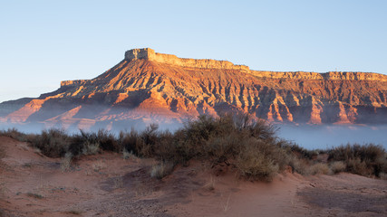 The first light of a winter day touches Hurricane mesa while a rare (for the desert) fog floats...
