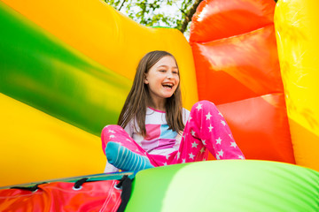 Happy little girl having lots of fun on a jumping castle during sliding.