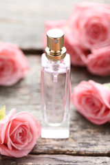 Obraz na płótnie Canvas Perfume bottle with roses on wooden table