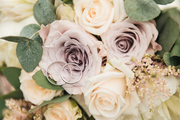 Beautiful wedding rings on the background of the bride's bouquet in pastel colors