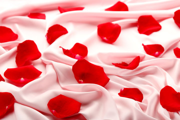 Red rose petals on pink satin cloth