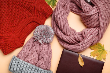 Fototapeta na wymiar Knitted sweater with scarf, hat and autumn leafs on beige background