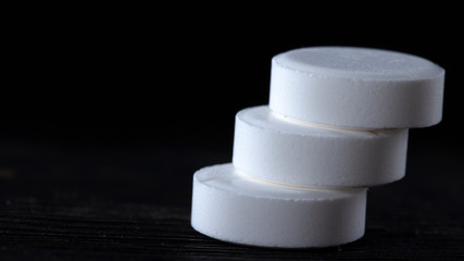 Three white pill on black background close up