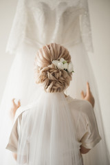 Stylish bride hairstyle, back view on the background of the wedding dress