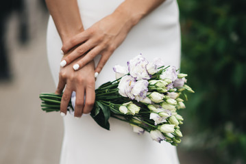 Obraz na płótnie Canvas Stylish minimalist wedding bouquet of eustoma in the hands of the bride