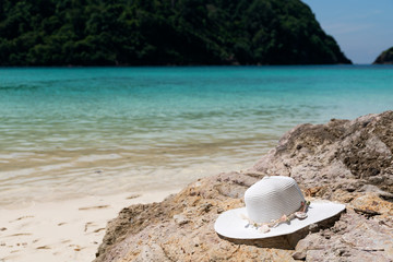 Fototapeta na wymiar White female hat on the stone on the tropical beach.