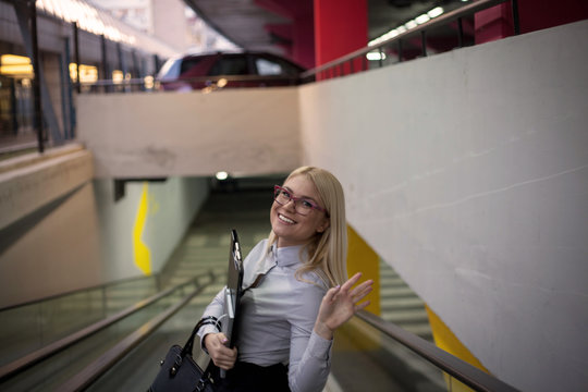 Confident woman with suitcase on escalator.