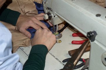 The hands of the working person at the sewing machine. No face.