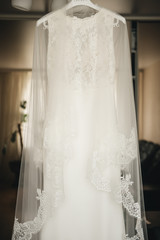 Fototapeta na wymiar The bride's wedding dress hangs on a chandelier in a bright room