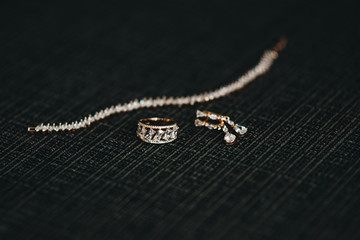 Women's wedding jewelry (earrings, ring and bracelet) on a dark background, selective focus