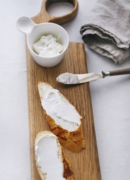 Close up of goat cheese spread onto bread on a wooden board