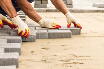 workers lay paving tiles, construction of brick pavement, close up architecture background