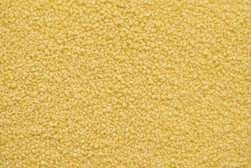 Couscous is a steamed balls of crushed durum wheat semolina. Couscous is a staple food throughout the North African cuisines. Top view, abstract background for your design