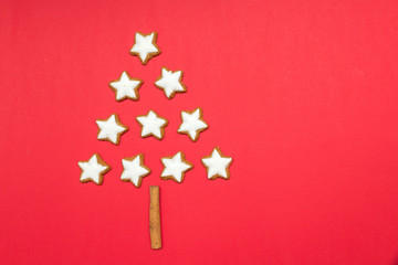 Fototapeta na wymiar Zimtsterne formen Weihnachtsbaum auf rotem Hintergrund