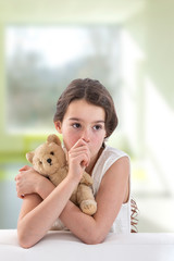 Teen girl lovingly holding a teddy bear sucking her thumb