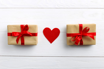 Gift with red ribbon and hearts on white wooden background. Women's or Valentine's Day. Place for text, copy space.