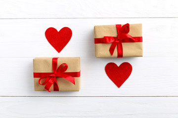 Gift with red ribbon and hearts on white wooden background. Women's or Valentine's Day. Place for text, copy space.