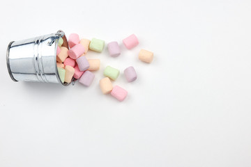 scattered from a small pail of marshmallow on a white background. copy space. vertical view. sweet...
