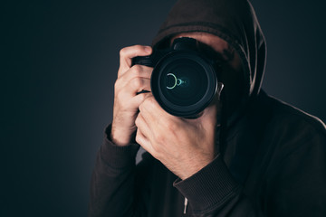 Hooded photographer behindDSLR camera