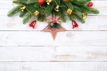 Christmas background concept. Top view of Christmas tree with spruce branches, pine cones, red berries and golden star on white wooden background.