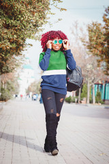 Charming African woman with blue sunglasses. Fashionable and stylish girl walking around the street
