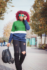 Charming African woman with blue sunglasses. Fashionable and stylish girl walking around the street