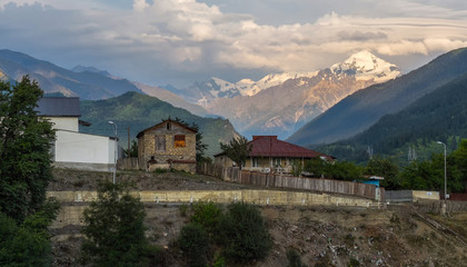 Fototapeta na wymiar Svan village view with Tetnuldi mountain on background and river slope with garbage