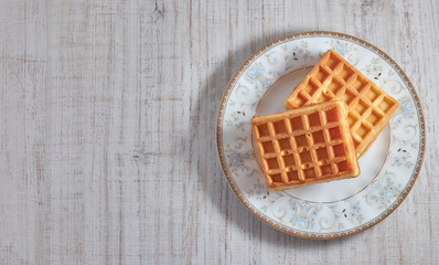 Obraz na płótnie Canvas Top view sweet fresh Viennese waffles on plate isolated on wooden table. copy space. European for breakfast.