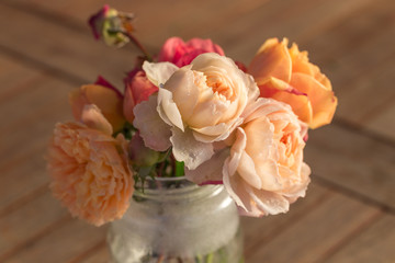 Bouquet of English roses with hoarfrost on the petals on the old wooden table, rustic style.