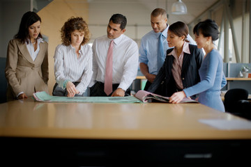 Mid-adult business people looking over plans in an office.